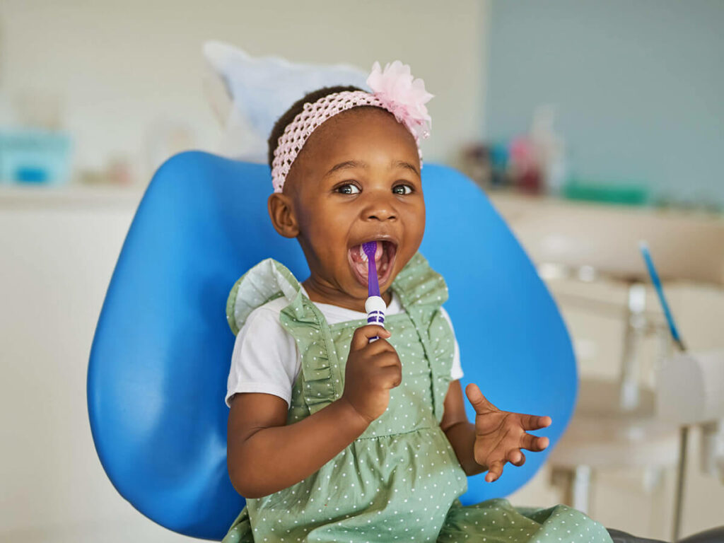 Toddler learning how to brush teeth at dentists office