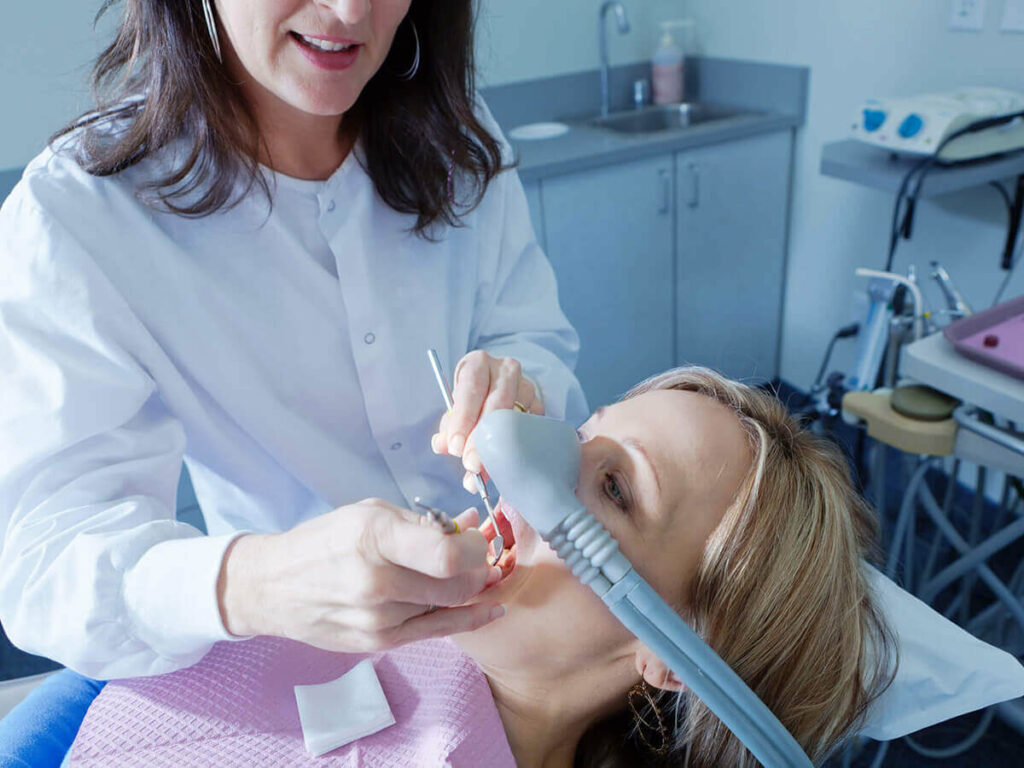 Dentist sedating patient for dental procedure
