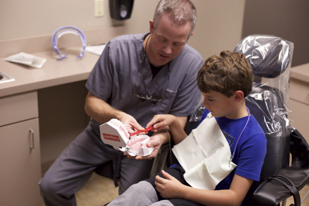 Dentist showing boy how to brush teeth