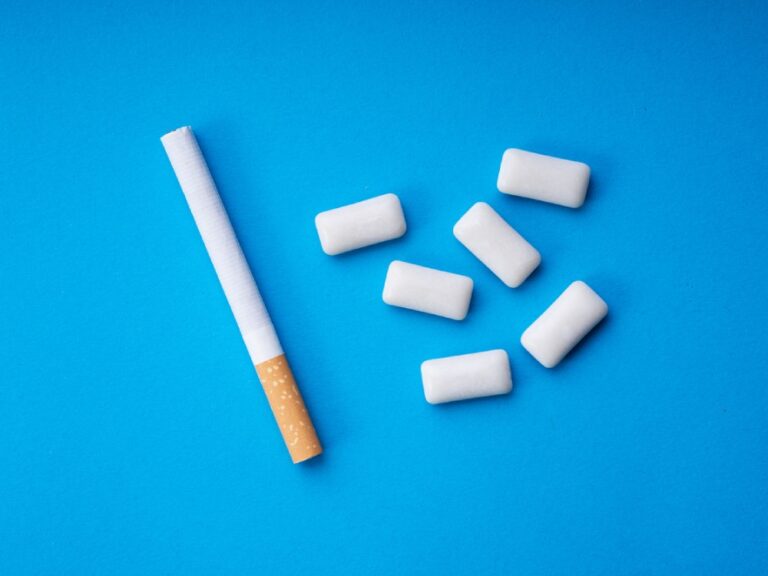 Cigarette and nicotine gum on blue background